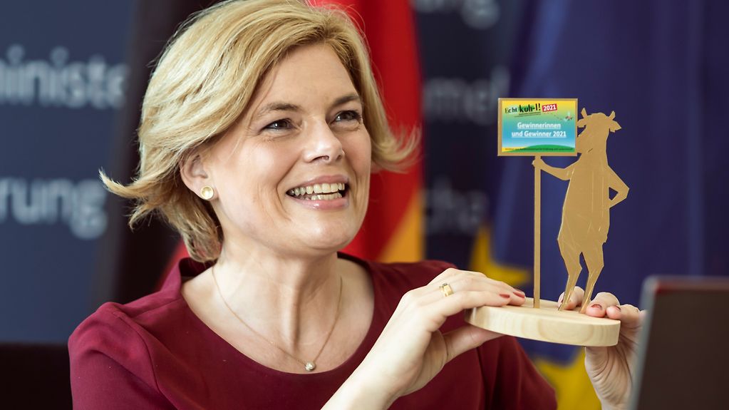 Bundeslandwirtschaftsministerin Julia Kloeckner (CDU) hält die Trophäe „Kuh-le Kuh“ in Gold für die Gewinnerinnen und Gewinner des Schulwettbewerbs „Echt kuh-l“ hoch.