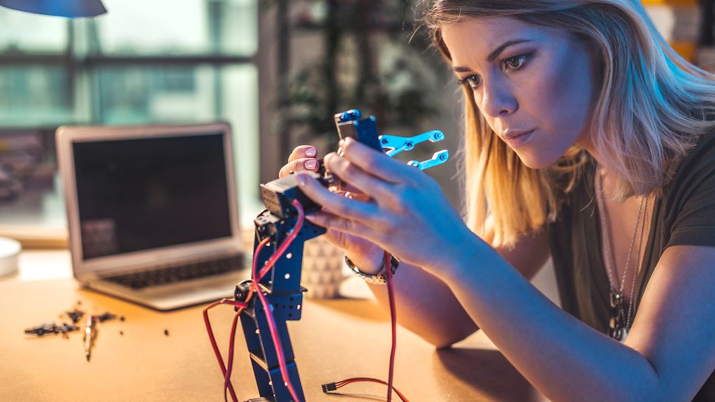 Young woman working on robot arm