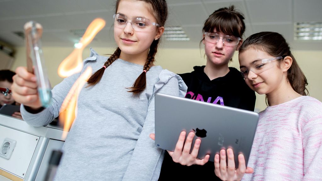 Mehrere Schülerinnen experimentieren während des Unterrichts im Fach Chemie und dokumentieren die Ergebnisse mit einem iPad. 