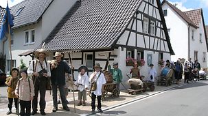 Meher bäuerlich gekleidete Personen (Männer und Kinder) vor dem Dorfmuseum des Teilortes Nordhausen.