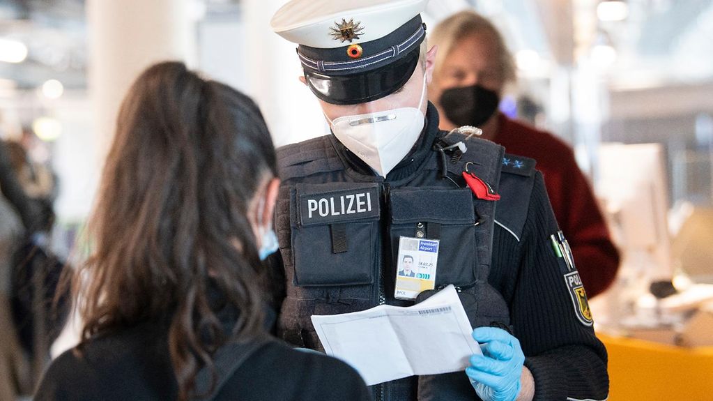 Eine Bundespolizistin kontrolliert edie Papiere einer Reisenden am Flughafen Frankfurt/Main.