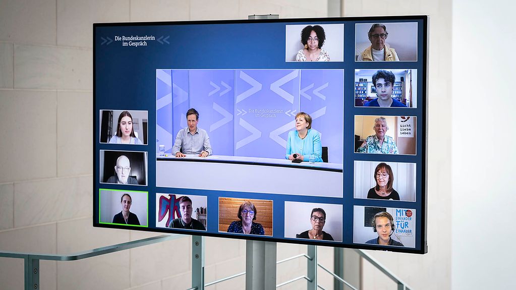 Ein Monitor zeigt die Teilnehmerinnen und Teilnehmer des Bürerdialogs von Kanzlerin Merkel zum Zusammenhalt der Generationen.