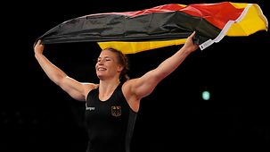 Aline Rotter Focken jubelt über olympisches Gold und trägt eine Deutschland-Fahne.