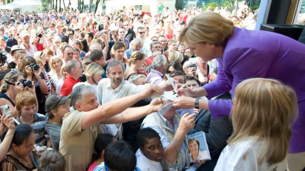 Bundeskanzlerin Merkel gibt einem Besucher ein Autogramm