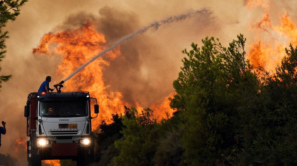 Feuerwehrleute versuchen mit Wasserwerfern einen Waldbrand im Norden Athens unter Kontrolle zu bringen.