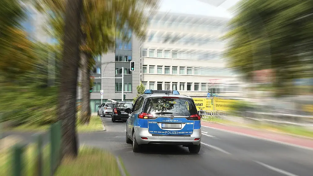 Polizeifahrzeug vor einer grünen Ampel