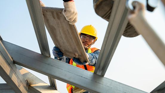 Ein Bauarbeiter arbeitet beim Hausbau auf dem Dach.
