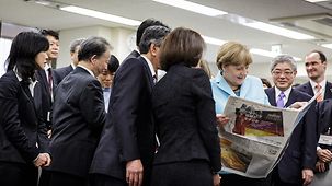 Chancellor Angela Merkel reads during a visit to the offices of the daily newspaper "Asahi Shimbun".