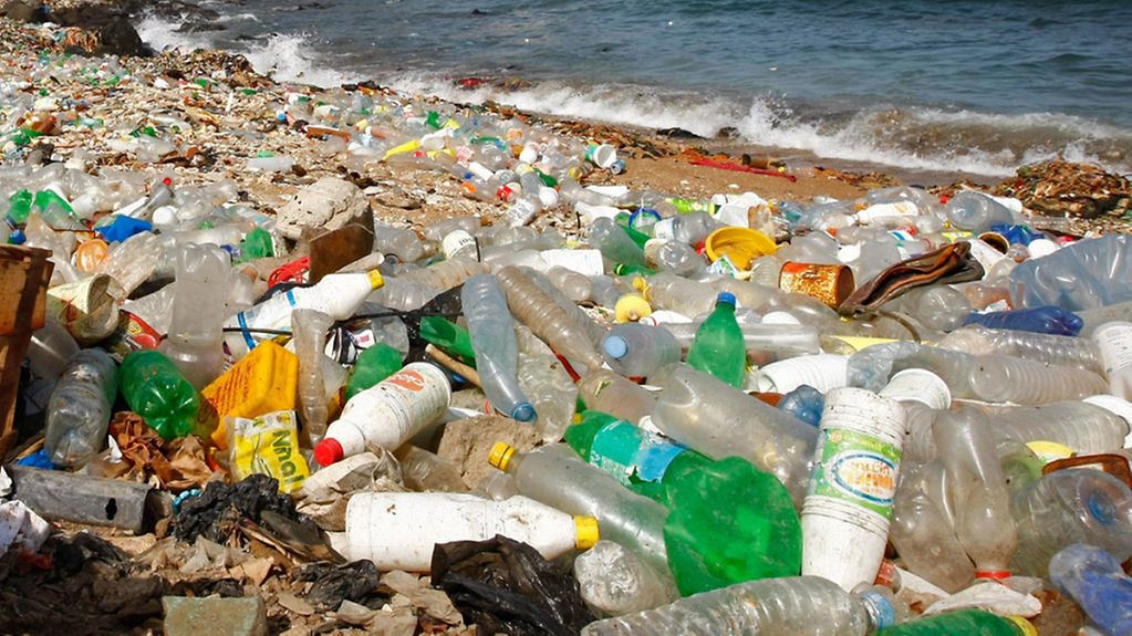Plastikmüll am Strand, im Hintergrund das Meer