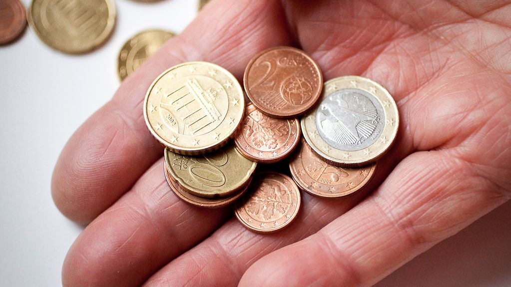 Euromünzen werden in einer Hand gezählt.