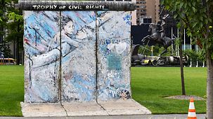 Pan de trois sections du mur de Berlin avec en arrière-plan le bâtiment des Nations Unies