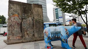 Drei Segmente der Berliner Mauer und ein Berliner Bär auf dem Berliner Platz.
