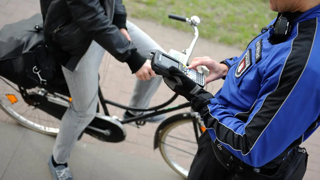Ein Leiter einer Fahrradstaffel schreibt einen Radfahrer auf, der eine rote Ampel missachtet hat