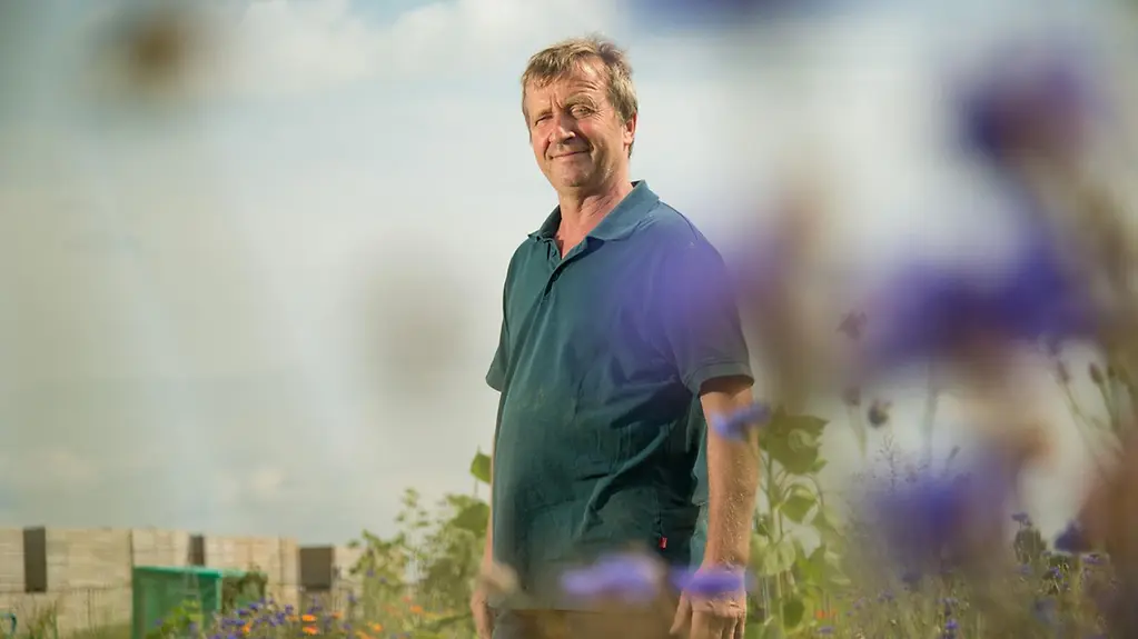 Christoph Leiders steht auf einem Feld mit Wildblumen.