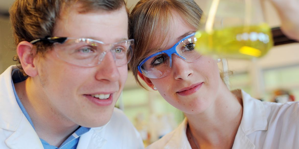 zwei Wissenschaftler schauen sich ein Reagenzglas an