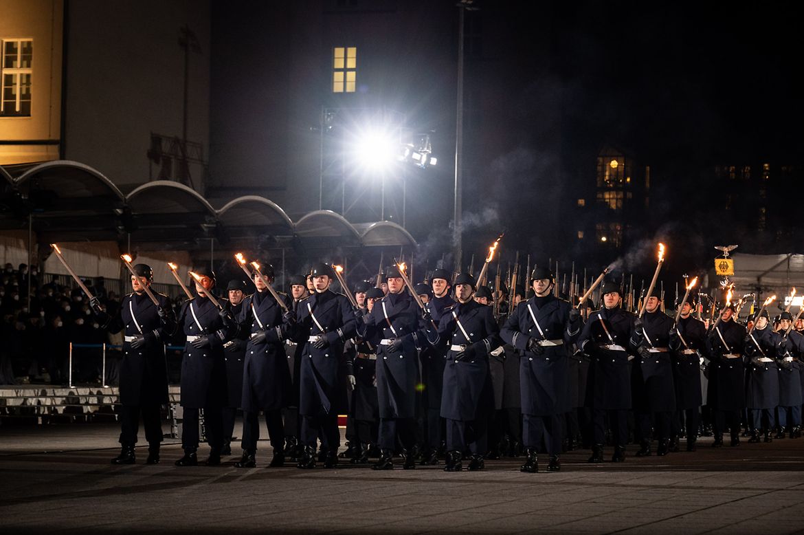 Bundeswehrsoldaten mit Fackeln marschieren bei einem Großen Zapfenstreich.