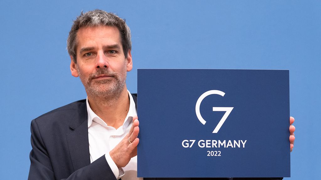 Regierungssprecher Hebestreit mit dem Logo der deutschen G7-Präsidentschaft.