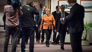 Chancellor Angela Merkel walks along a corridor.