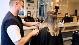 Friseur schneidet einer Kundin im Salon die Haare.