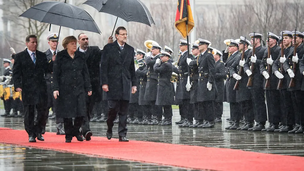 Angela Merkel and Mariano Rajoy with umbrellas
