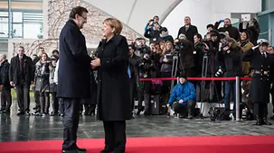Angela Merkel welcomes Mariano Rajoy in front of a group of journalists.