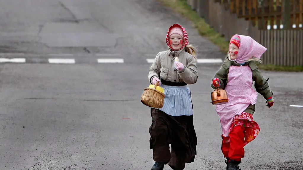 Zwei als Hexen verkleidete Mädchen laufen durch eine Straße in Schweden.