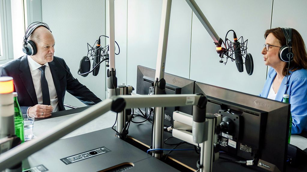La photo montre le chancelier Scholz dans un studio radio au côté d’Angela Ulrich, rédactrice à la RBB.