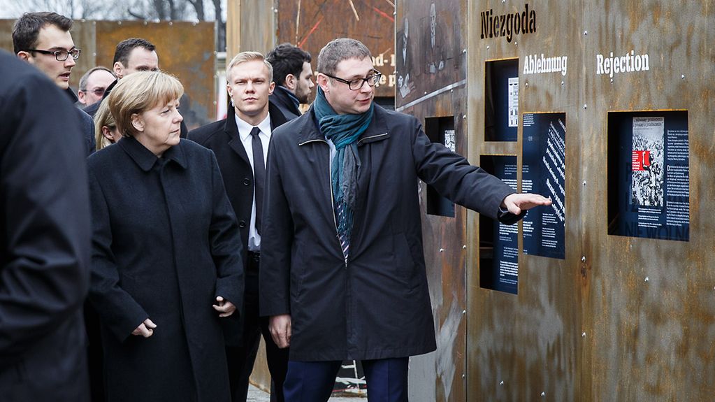 Federal Chancellor Angela Merkel walks through the "Courage and Reconciliation" ("Mut und Versöhnung") exhibition.