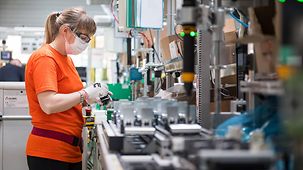 Eine Mitarbeiterin mit Mundschutz arbeitet an einem Werkstück in der Produktion der Schneider Electric Company in Pisek, Tschechien.