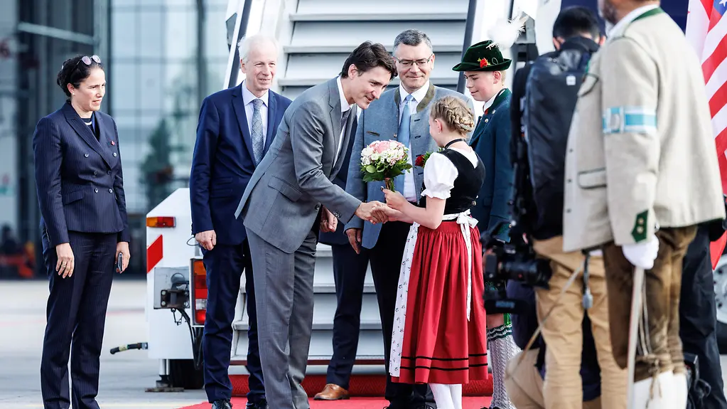 A girl in traditional Bavarian costume welcomes Canadian Prime Minister Justin Trudeau with a bouquet.