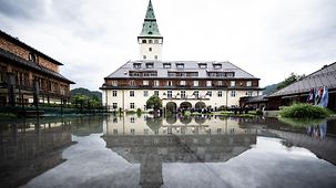 Schloss Elmau spiegelt sich auf einer Wasserfläche.