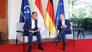 Le chancelier fédéral Olaf Scholz et le président indonésien Joko Widodo assis devant des drapeaux.