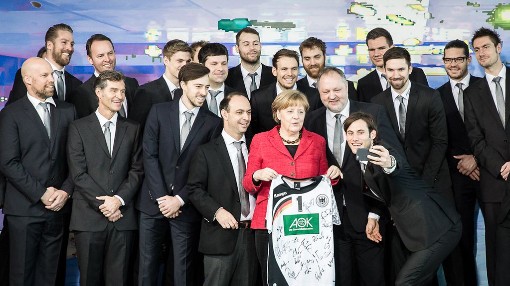 Uwe Gensheimer macht beim Gruppenfoto ein Selfie mit Bundeskanzlerin Angela Merkel.
