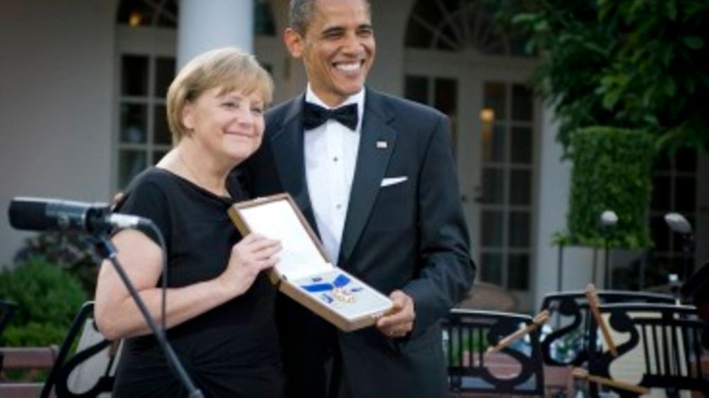 Angela Merkel hält die überreichte Medaille, neben ihr Barack Obama