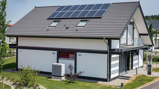 Haus mit Photovoltaik auf dem Dach und eine Luft-Luft-Wärmepumpe im Garten.