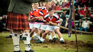 Ein Team steht am Start im Tauziehen-Wettbewerb, im Vordergrund ein Kampfrichter im Kilt. Braemar, Scotland
