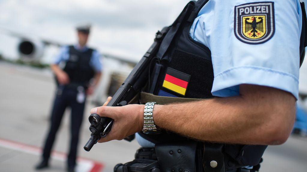 Beamte der Bundespolizei stehen mit schusssicheren Westen und einer Maschinenpistole vor einem Flugzeug auf dem Vorfeld vom Flughafen in München.