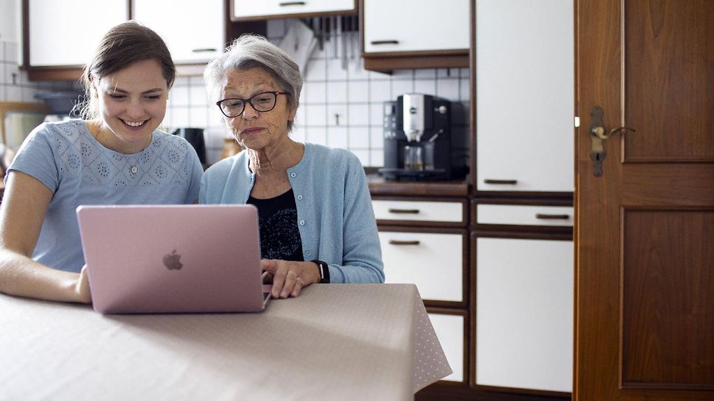 Das Foto zeigt Grossmutter und Enkeltochter am Laptop in der Küche.