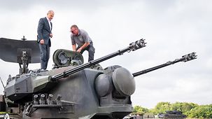 Federal Chancellor Olaf Scholz standing on a Gepard tank at the Putlos military training area.