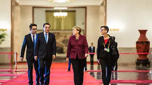 Chancellor Angela Merkel walks next to Chinese Prime Minister Li Keqiang.