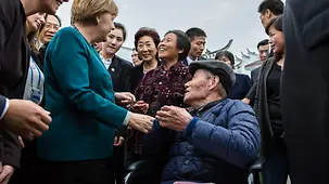 Chancellor Angela Merkel is welcomed in Shen Fu.