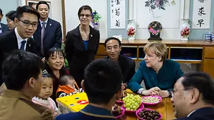 Chancellor Angela Merkel talks to a local farmer and his family.
