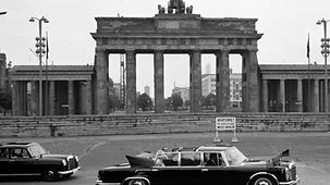 Ihr Besuch führt Elizabeth auch in das geteilte Berlin. Am Brandenburger Tor besichtigt sie zusammen mit Prinz Philip die Berliner Mauer.