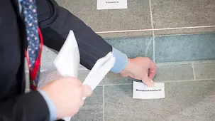 Ein Mitarbeiter positioniert das Schild der Bundeskanzlerin.