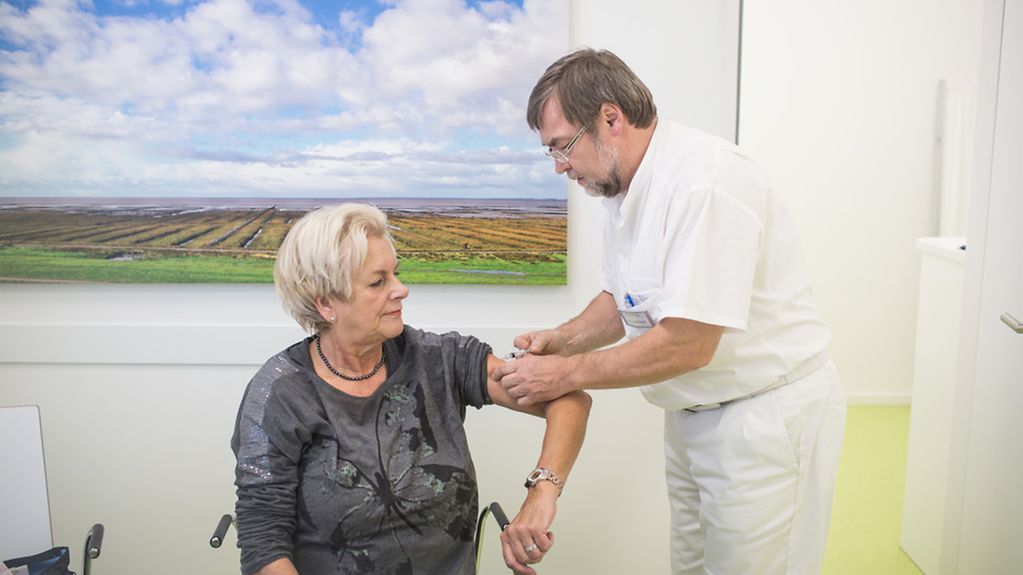 Arno Lindemann gibt einer Patientin eine Grippeimpfung.