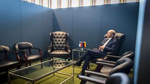 Bundeskanzler Olaf Scholz in einem Sessel im Rahmen eines bilateralen Gesprächs.
