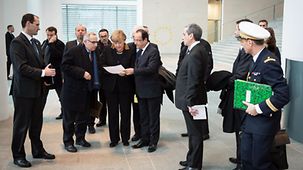 Merkel und Hollande mit dem Plan und Delegationsteilnehmern.