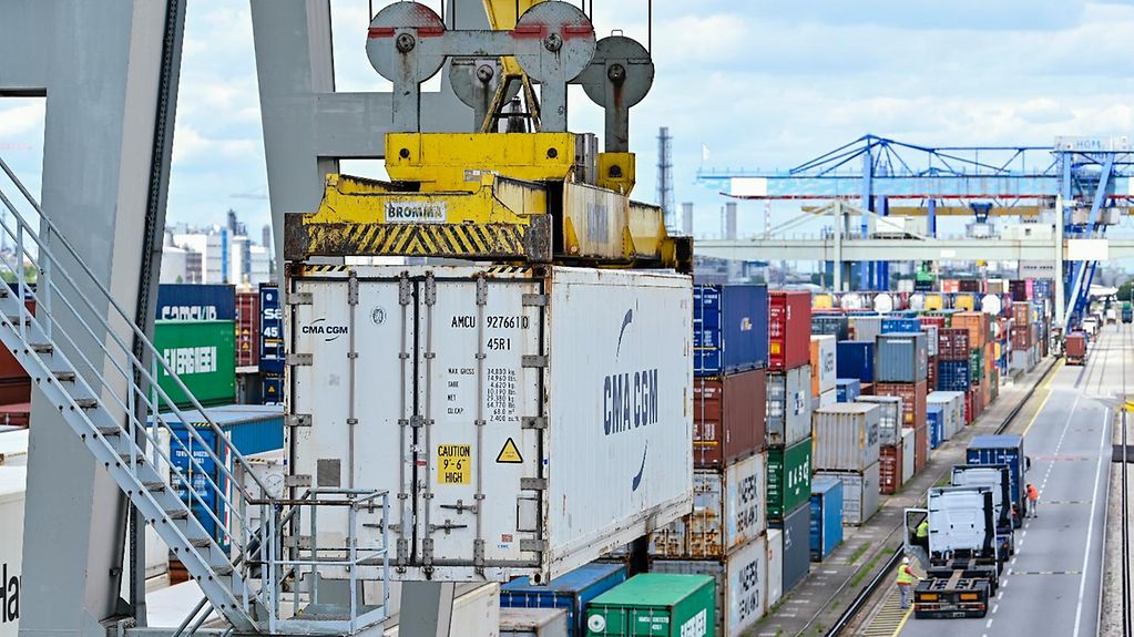Auf dem Bild ist zu sehen, wie ein Kran einen Container im Handelshafen des Rhein-Neckar-Hafens verlädt.