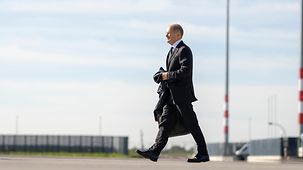Federal Chancellor Olaf Scholz walking on the grounds of the airport.