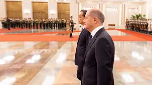 Bundeskanzler Olaf Scholz geht neben Li Keqiang, Chinas Premierminister.